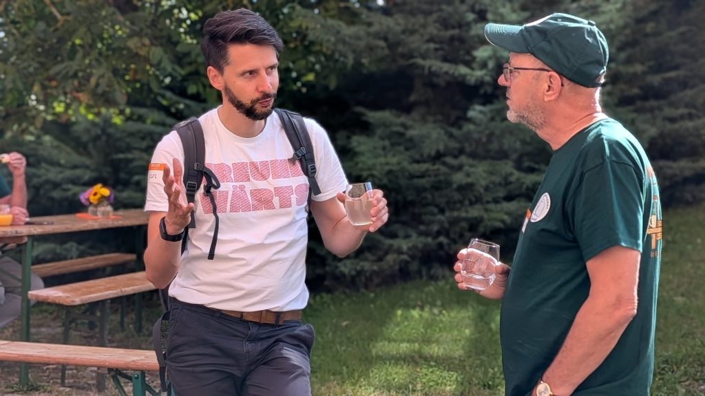 Zwei Teilnehmer im Gespräch im Schlossgarten, einer im freundwärts-Shirt