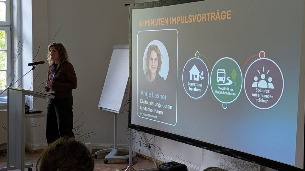 Rednerin am Pult, auf der Leinwand die Übersicht der Impulsvorträge