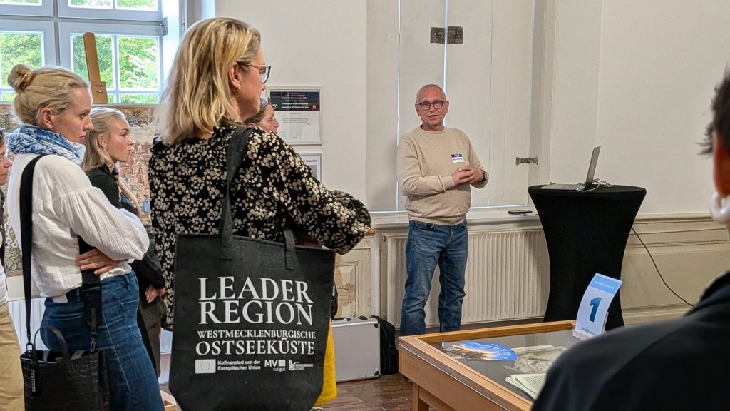 Teilnehmende im Foyer an den Stationen, eine mit LEADER-Tasche