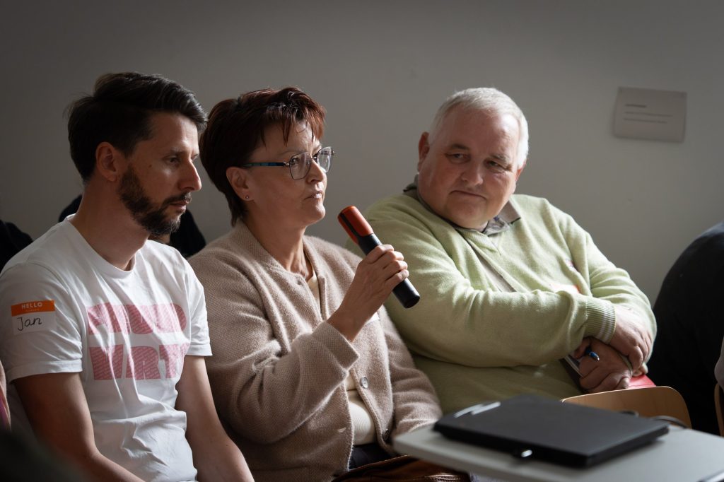 Wortmeldung aus dem Publikum, eine Frau mit Mikrofon zwischen zwei Männern