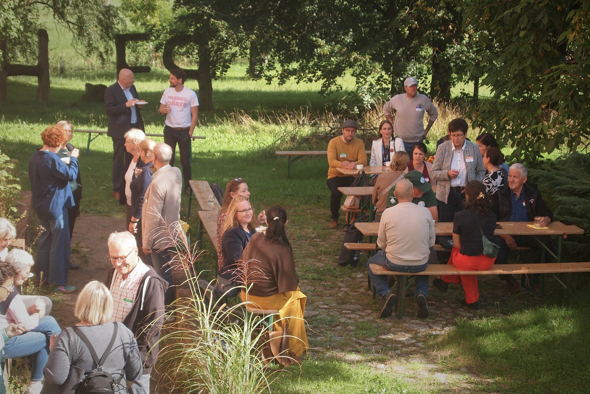Pause im Schlossgarten an Bierzeltgarnituren unter Bäumen