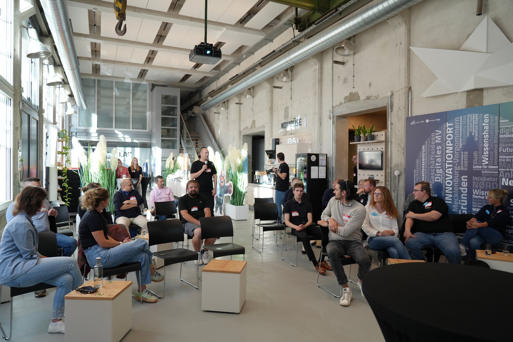 Stuhlkreis im Innovation Port während der Panelrunde, rund 28 Teilnehmende sitzen im Halbkreis um die Sprechenden