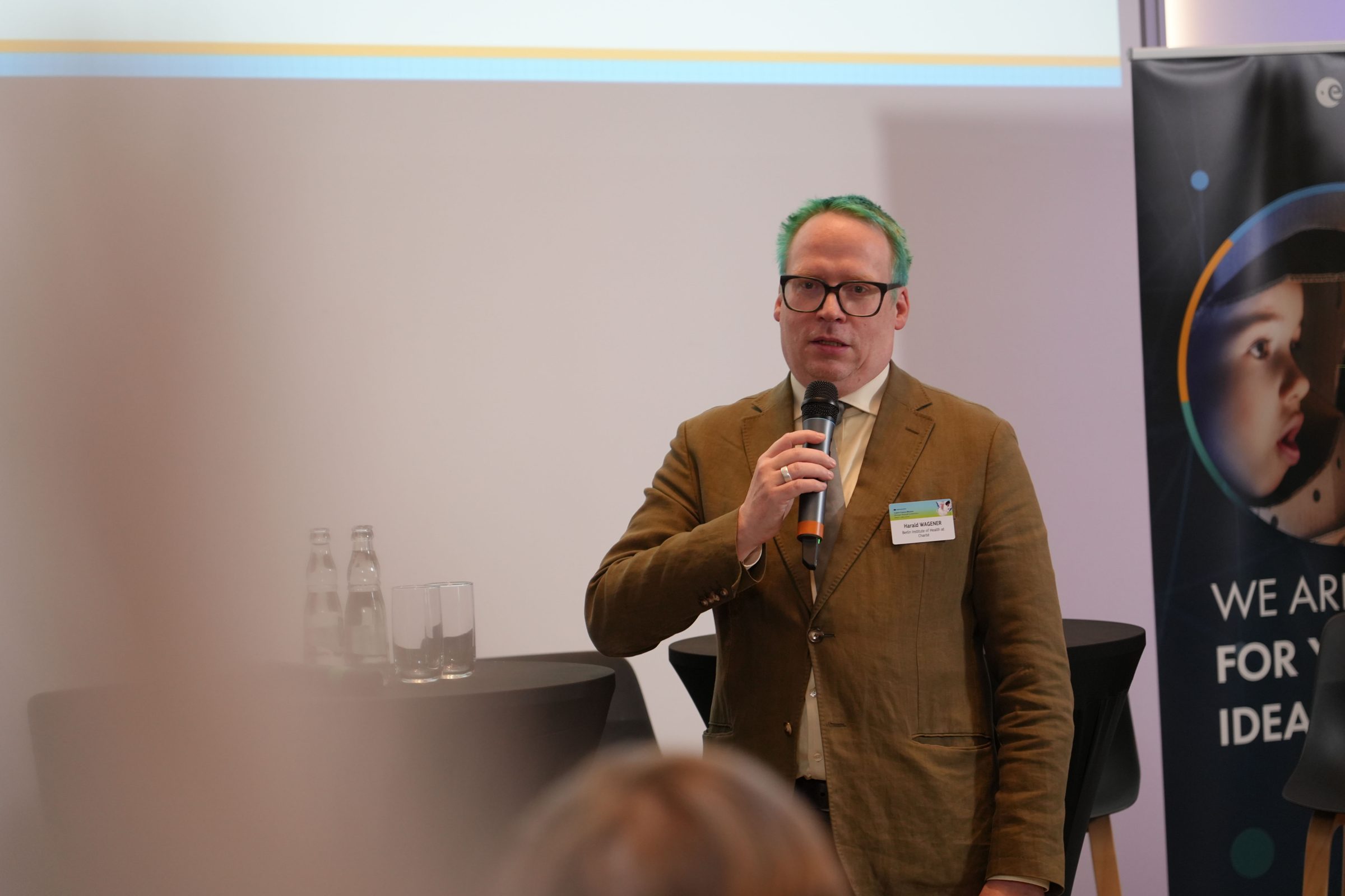 Harald Wagener im braunen Anzug spricht mit Mikrofon
